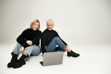 A mother and daughter share laughter while looking at a laptop together.