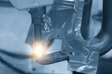 The automotive parts spot welding process by robotic system in the light blue scene with lighting...
