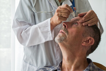 A doctor puts eyedrop medication into a man's eye during an appointment at the hospital.