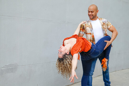 Couple dancing against a wall, with the man supporting the woman in a graceful dip.