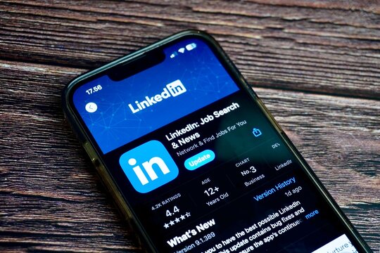 Jakarta, Indonesia - August 7th, 2024 - LinkedIn job search portal mobile application screen on app store isolated on horizontal ratio brown wooden surface background.