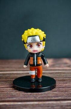 Jakarta, Indonesia - August 7th, 2024 - Naruto uzumaki small chibi style gacha prize figure toy isolated on vertical wooden table and black wall surface background.