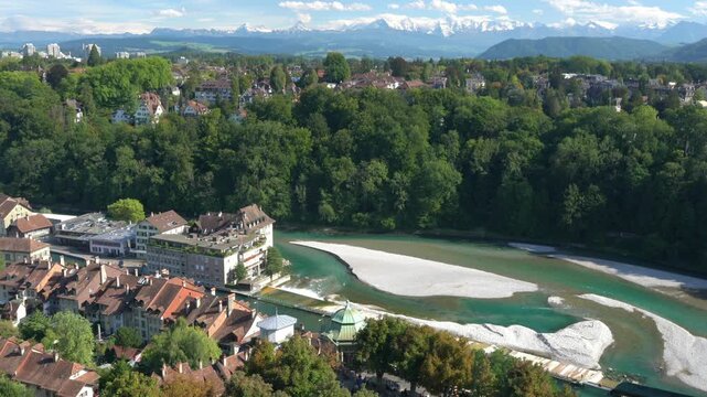 A beautiful view of a river with a town in the background. The river is green and the town is surrounded by trees