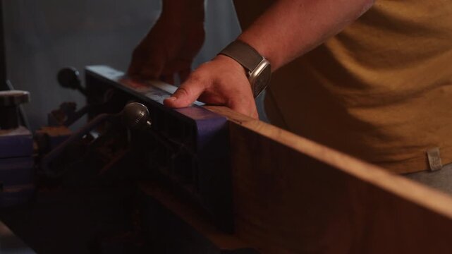 man sawing wood on a jointer in a home workshop