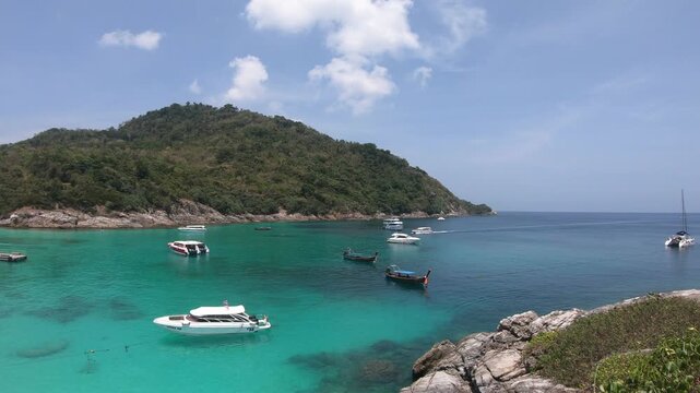 A beautiful beach with a lot of boats in the water. The sky is blue and the water is clear