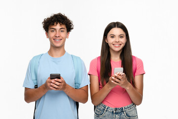 Smiling high school pupils students teenagers classmates boy girl friends in casual clothes with bags holding smart cell phones using mobile app looking at camera isolated over white background