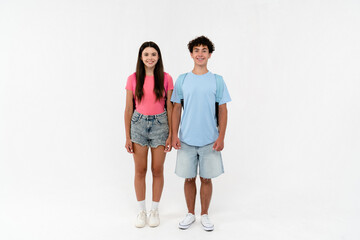 Fototapeta premium Full length of high school pupils students teenagers classmates boy and girl in casual clothes with bag standing posing looking at camera isolated on white background. Education back to school concept