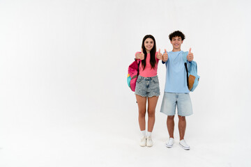 Full length size of high school pupils students teenagers classmates boy girl friends in casual with bags showing thumb up sign gesture isolated on white background copy space. Education concept