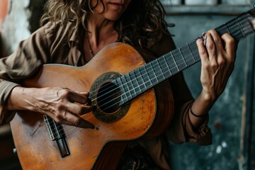 Obraz premium Close-up of a woman playing an acoustic guitar with focus on her hands and the instrument
