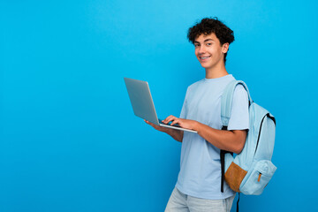 Smiling boy guy high school male pupil student teenager with backpack holding using laptop computer...