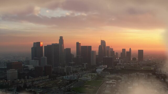 Los Angeles Aerial View At Sunset, Skyscrapers In The Financial District Piercing The Clouds. Fluffy Clouds Drift Through The Scene, Capturing The Urban Essence Of California And The United States.