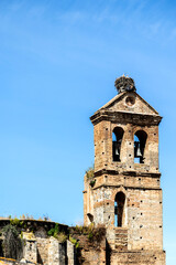 Fototapeta premium nido de cigüeña blanca en un campanario antiguo de piedra con dos campanas en el campanario en Niebla , Huelva,España