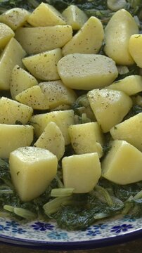 Leaf beet with potatoes, garlic, and olive oil. Croatian Blitva dish. Table spin, copy space, vertical video.