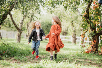 Fototapeta premium Children whirling, dancing plays on meadow. Girls having fun. Cute little longhair blonde girl dancing at sunset park. Selective focus. innocence and happiness of childhood