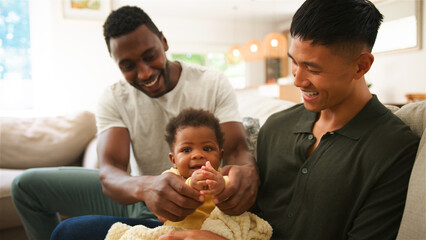 Diverse Same Sex Male Couple Playing With Their Baby in a Cozy Living Room