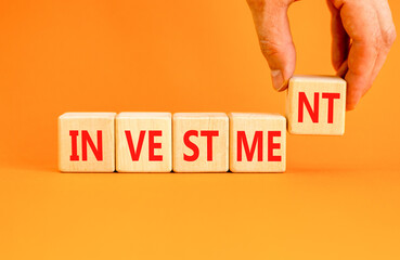 Investment symbol. Concept word Investment on beautiful wooden blocks. Beautiful orange background....