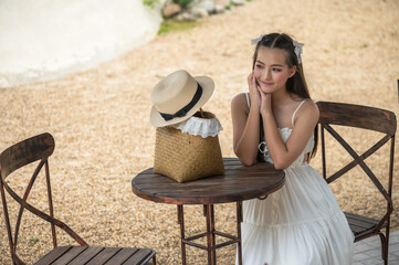 Cute girl in white casual dress sitting and relaxing in cafe
