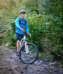 Obraz premium Man, bicycle and exercise on path in forest for recreational activity, skill development and training for competition. Cyclist, mountain bike and trail for outdoor adventure in nature and workout.