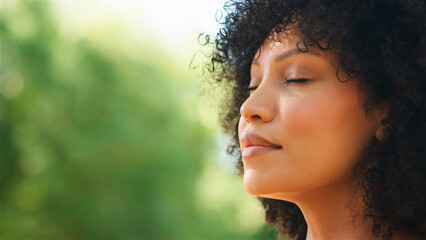 Woman Meditating Outdoors With Eyes Closed in a Natural Setting on a Sunny Day
