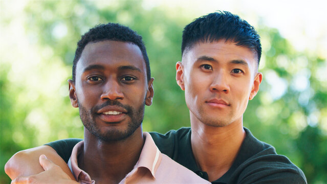 Same Sex Male Couple or Friends Embracing Outdoors in a Park During Sunny Day