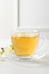 Aromatic jasmine tea in cup and flowers on white table