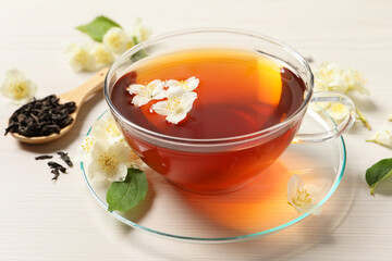 Hot jasmine tea in cup and flowers on white wooden table
