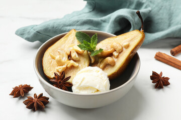 Delicious baked pears with nuts, ice cream, anise stars, mint and honey in bowl on white table, closeup
