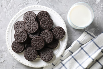 Tasty sandwich cookies and milk on light grey table, top view