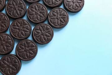 Tasty sandwich cookies on light blue background, top view. Space for text