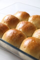 Delicious dough balls in baking dish on white wooden table, closeup