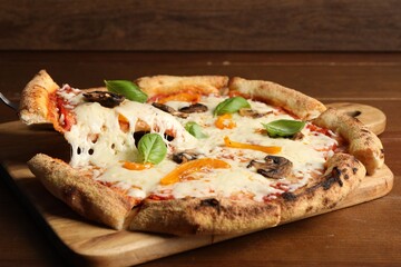 Taking piece of delicious vegetarian pizza at wooden table, closeup