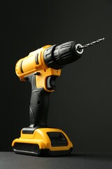 Modern cordless electric drill on grey table against black background