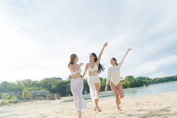 Asian girlfriends in matching white outfits having a great time by the beach 