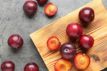 Fresh plums on grey textured table, flat lay