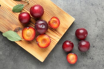 Fresh plums on grey textured table, flat lay