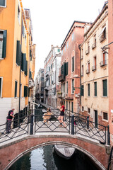 Obraz premium Eine junge Frau steht mit ihrem falbenfarbenen Eurasier auf einer Brücke über einem schmalen Kanal in Venedig. Der Eurasier macht Männchen