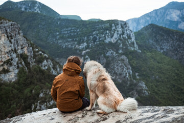 Junge Frau sitzt an der Verdonschlucht mit Blick aufs Tal in Mitten der Natur, genie&szlig;t die aussicht und kuschelt mit ihrem Eurasier