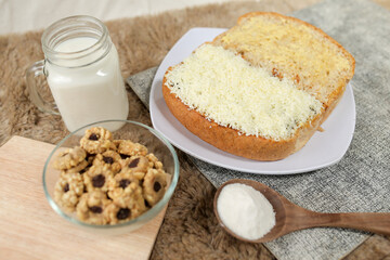 Bread with cheese, sweetened condensed milk, and butter. With white milk and snack on a table for breakfast	
