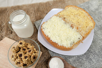 Bread with cheese, sweetened condensed milk, and butter. With white milk and snack on a table for breakfast	
