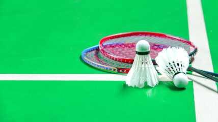 White badminton shuttlecocks and badminton rackets on green floor indoor badminton court