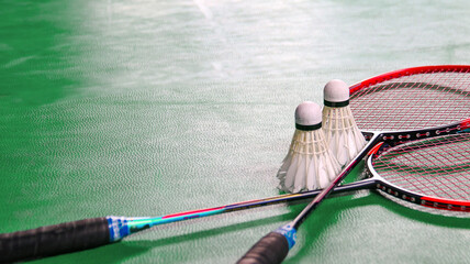 White badminton shuttlecocks and badminton rackets on green floor indoor badminton court
