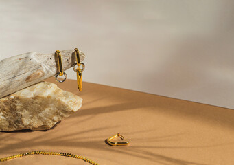 Golden earrings on pastel beige background with shadow. Stylish jewellery set