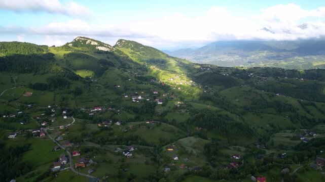 High angle flyover footage over the magnificent picturesque village of Magura in Brasov region of the Romanian Carpati mountains. Drone shot of the gem of romanian tourism on a green summer day.
