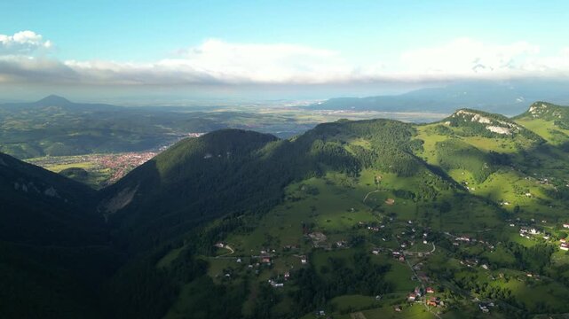 High angle flyover footage over the magnificent picturesque village of Magura in Brasov region of the Romanian Carpati mountains. Drone shot of the gem of romanian tourism on a green summer day.
