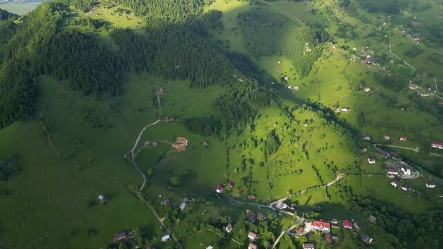 High angle flyover footage over the magnificent picturesque village of Magura in Brasov region of the Romanian Carpati mountains. Drone shot of the gem of romanian tourism on a green summer day.
