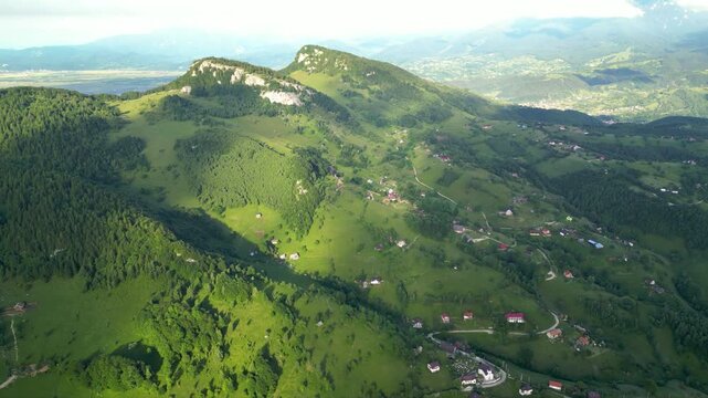 High angle flyover footage over the magnificent picturesque village of Magura in Brasov region of the Romanian Carpati mountains. Drone shot of the gem of romanian tourism on a green summer day.
