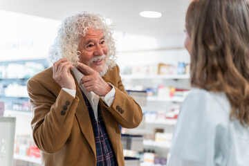 Elderly man showing his hair at the pharmacy, speaking to a pharmacist