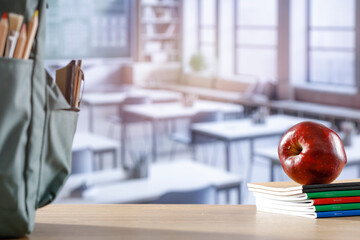 School stuff and schoolbag on a wooden desk in classroom interior. Copy space.