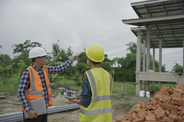 Fototapeta premium Professional architect engineer with hard hat and blueprint at building construction site house building permit background. Architects looking at blueprints. Construction and engineering industry