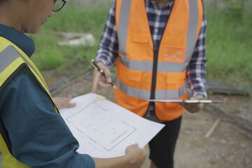 Fototapeta premium Professional architect engineer with hard hat and blueprint at building construction site house building permit background. Architects looking at blueprints. Construction and engineering industry